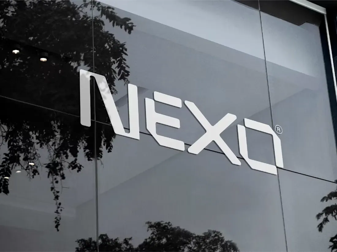 NEXO dimensional wordmark mounted on a contemporary glass building.