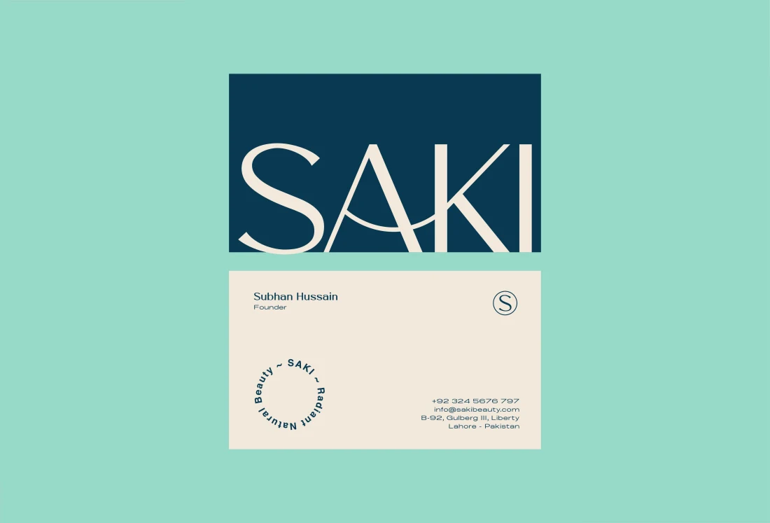 SAKI business cards in cream and deep teal against a mint background.